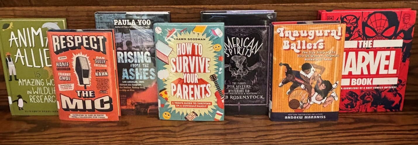 Books facing cover out on a wooden shelf