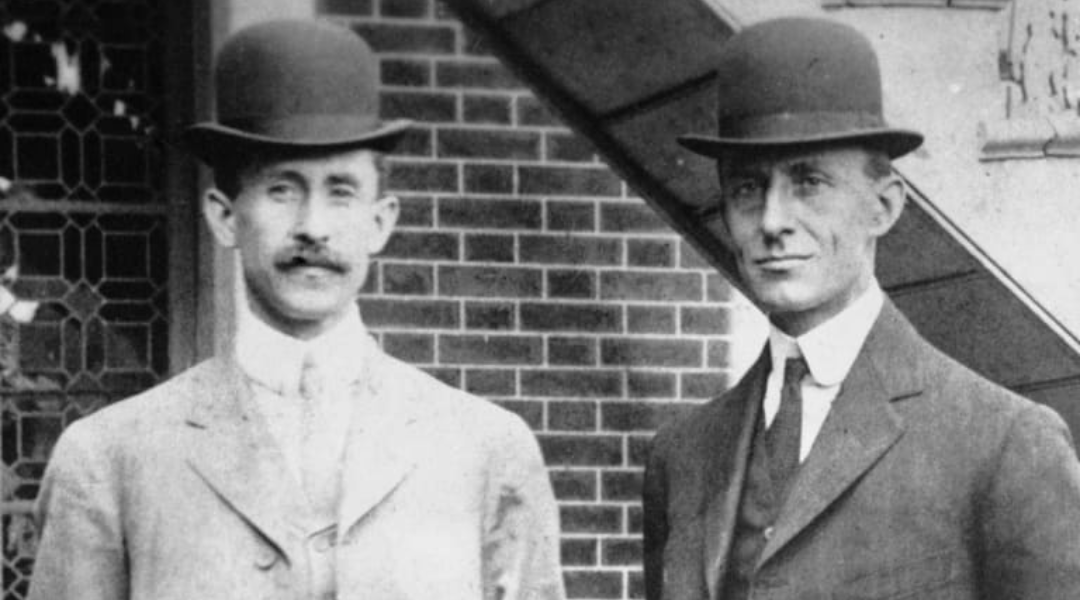 The Wright Brothers pose for a picture, both wearing bowler hats.