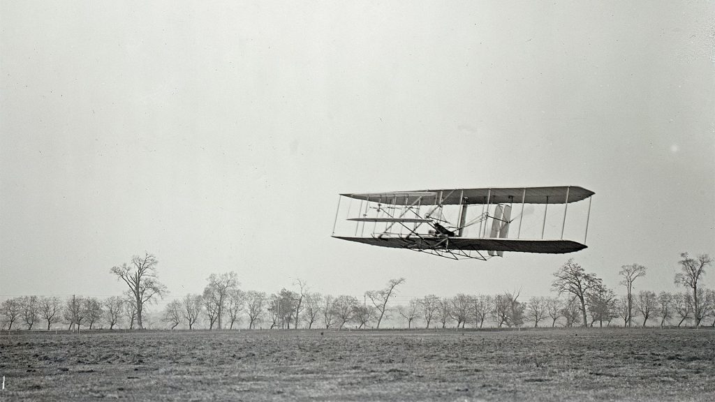 The Wright Flyer II soars above the ground.